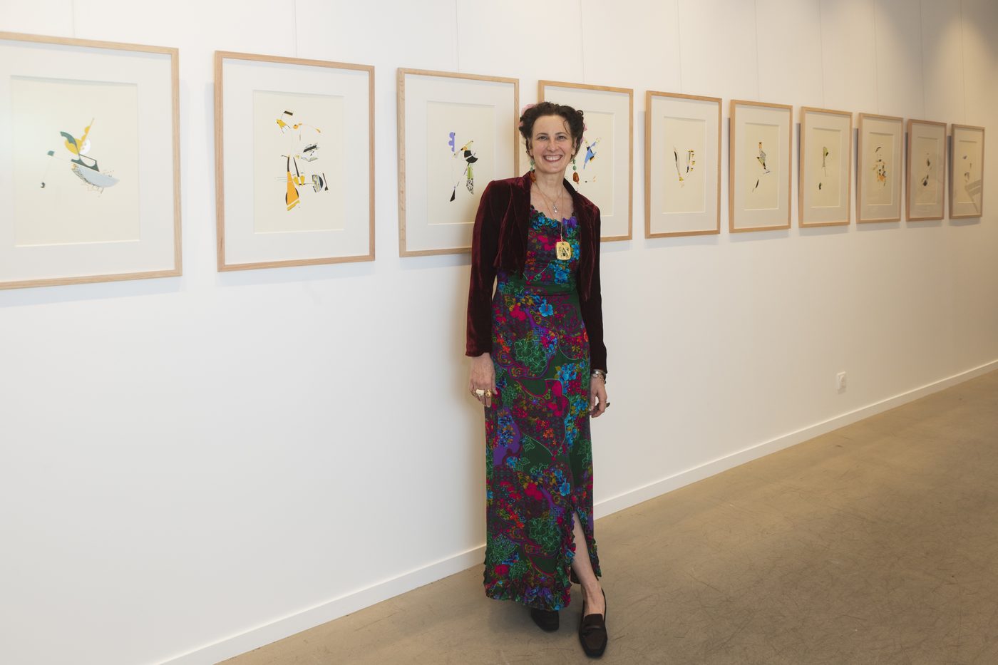 Jessica Anne Schwartz beside a long row of her framed drawings.