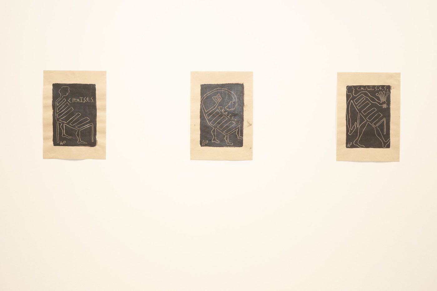 Three black-and-kraft works on paper hung in a row.